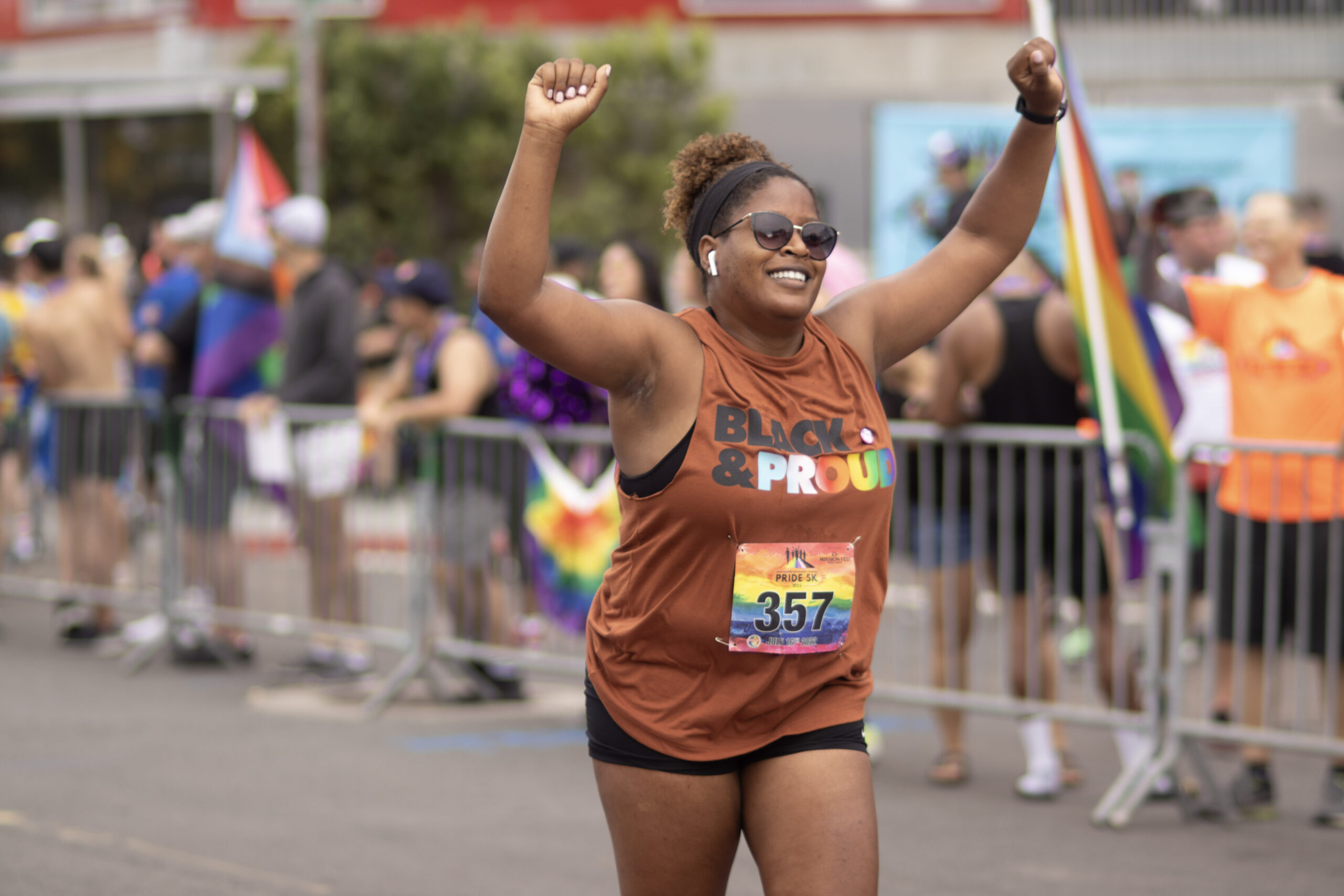 person running at the Pride 5k with their hands raised in the air